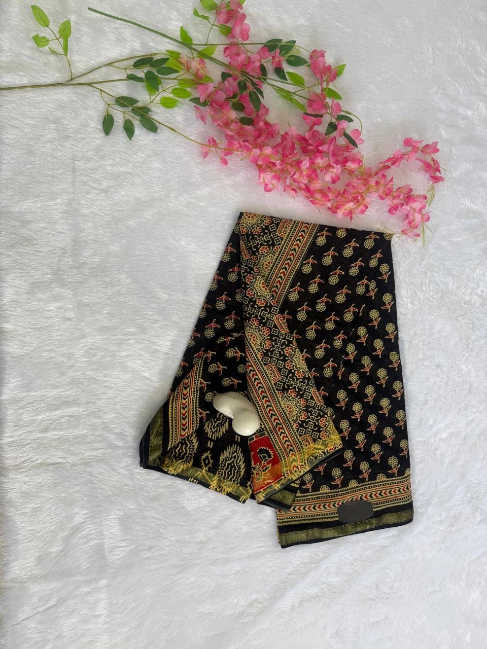 Solid black saree paired with a tussar beige Kalamkari style floral printed border and striped pallu.